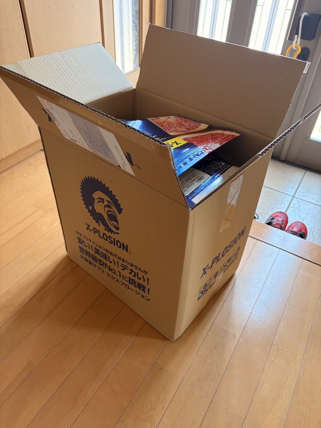 エクスプロージョンの段ボール箱。「安い！美味い！デカい！世界最安No.1に挑戦！」と書かれている